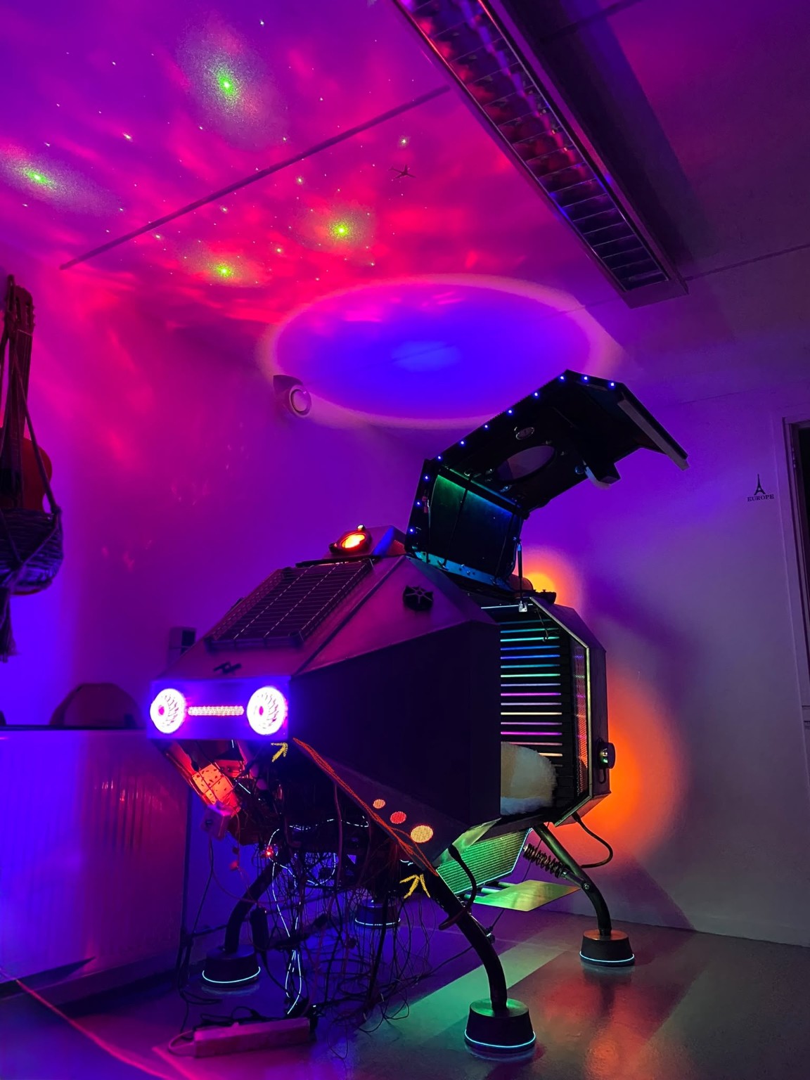 Large illuminated machine installation beneath coloured projected light